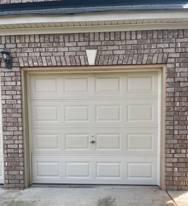 Closed white garage door set in a brick house exterior