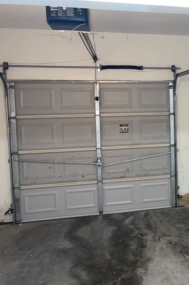 Two-car garage door taped shut with a visible crack, front of a house.