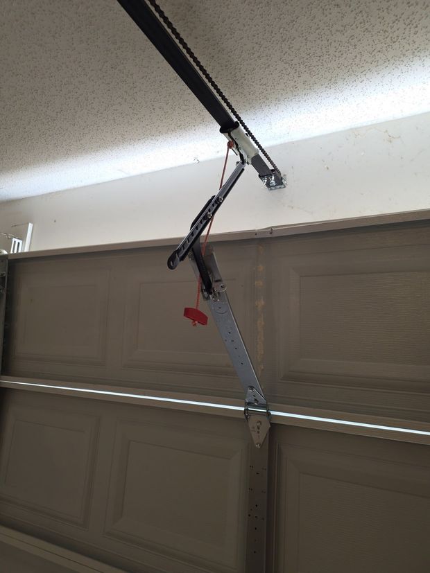 Garage door opener arm hanging loose from the ceiling rail, with a red release handle visible.