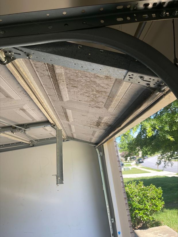 Damaged garage ceiling with sagging insulation and exposed framing near the open door