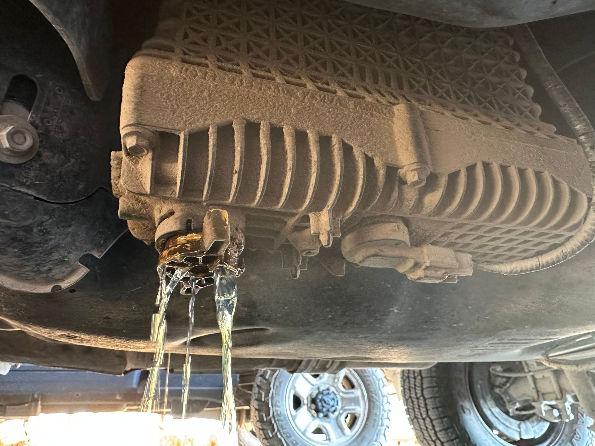 Undercarriage of a vehicle with fluid leaking from a damaged oil pan onto the ground