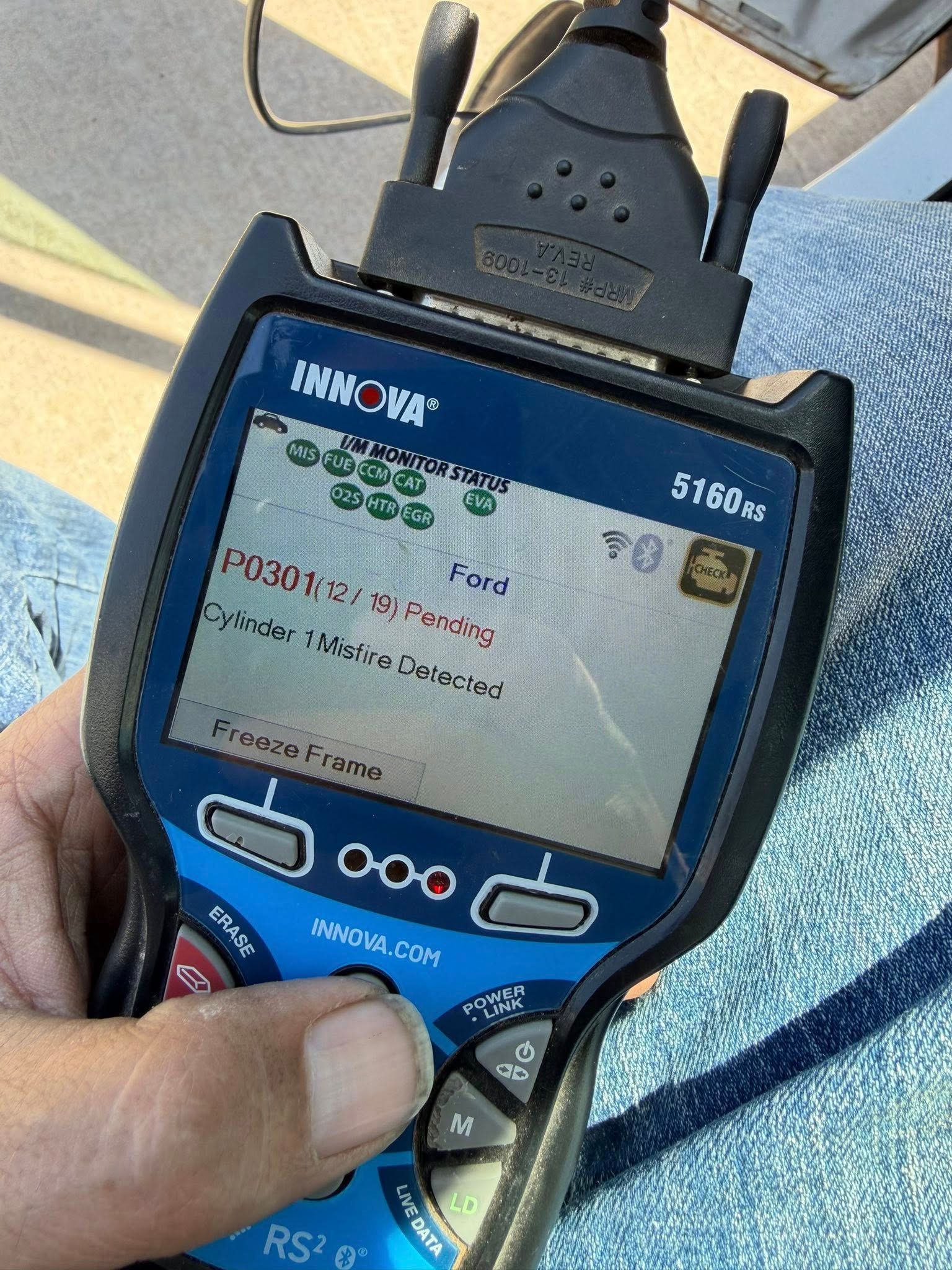 Handheld HIKOKI device showing a text menu, held in a person's hand outdoors.