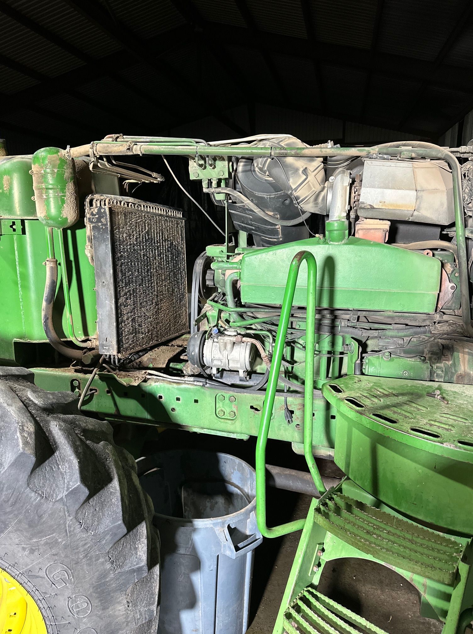 Close-up of a green industrial machine with exposed components and large tires in a dim indoor setting