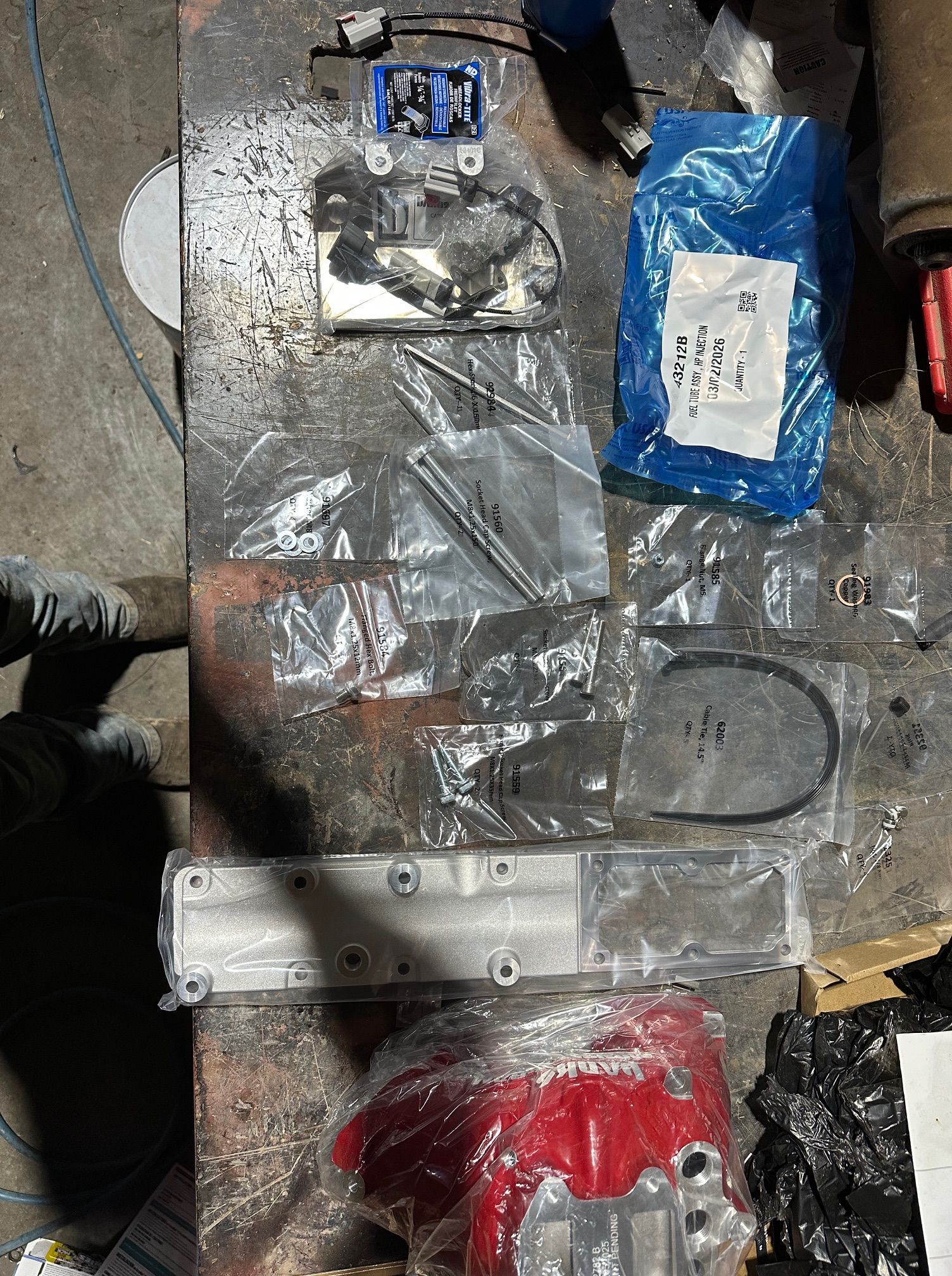 Assorted metal and plastic parts in clear packaging spread on a concrete floor