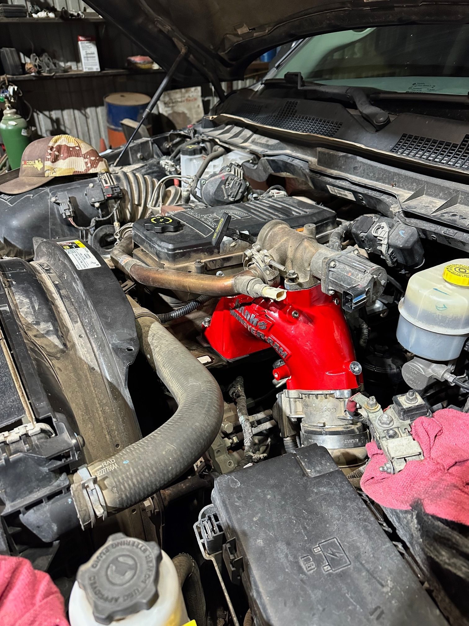 Engine bay with a bright red intake pipe and open hood in a workshop or garage