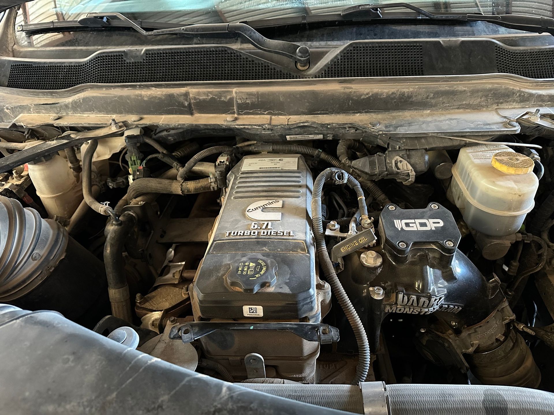 Car engine bay with dusty components and visible reservoir caps under the hood