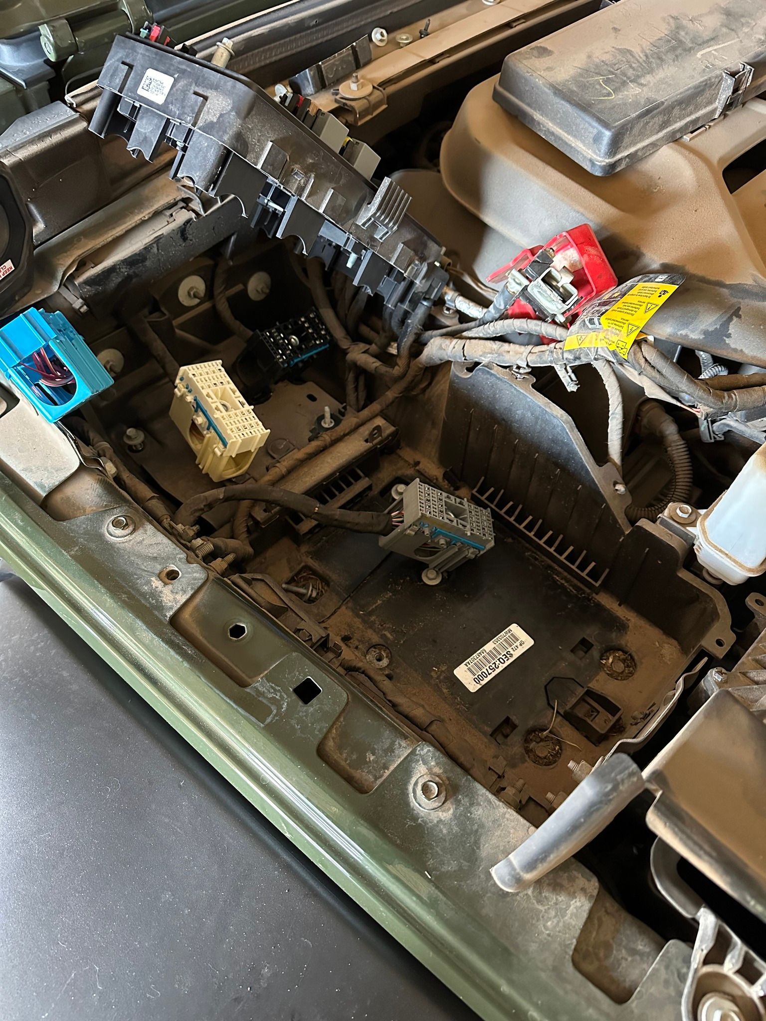 Open car dashboard cavity with exposed wiring, vents, and dusty black components in green interior.