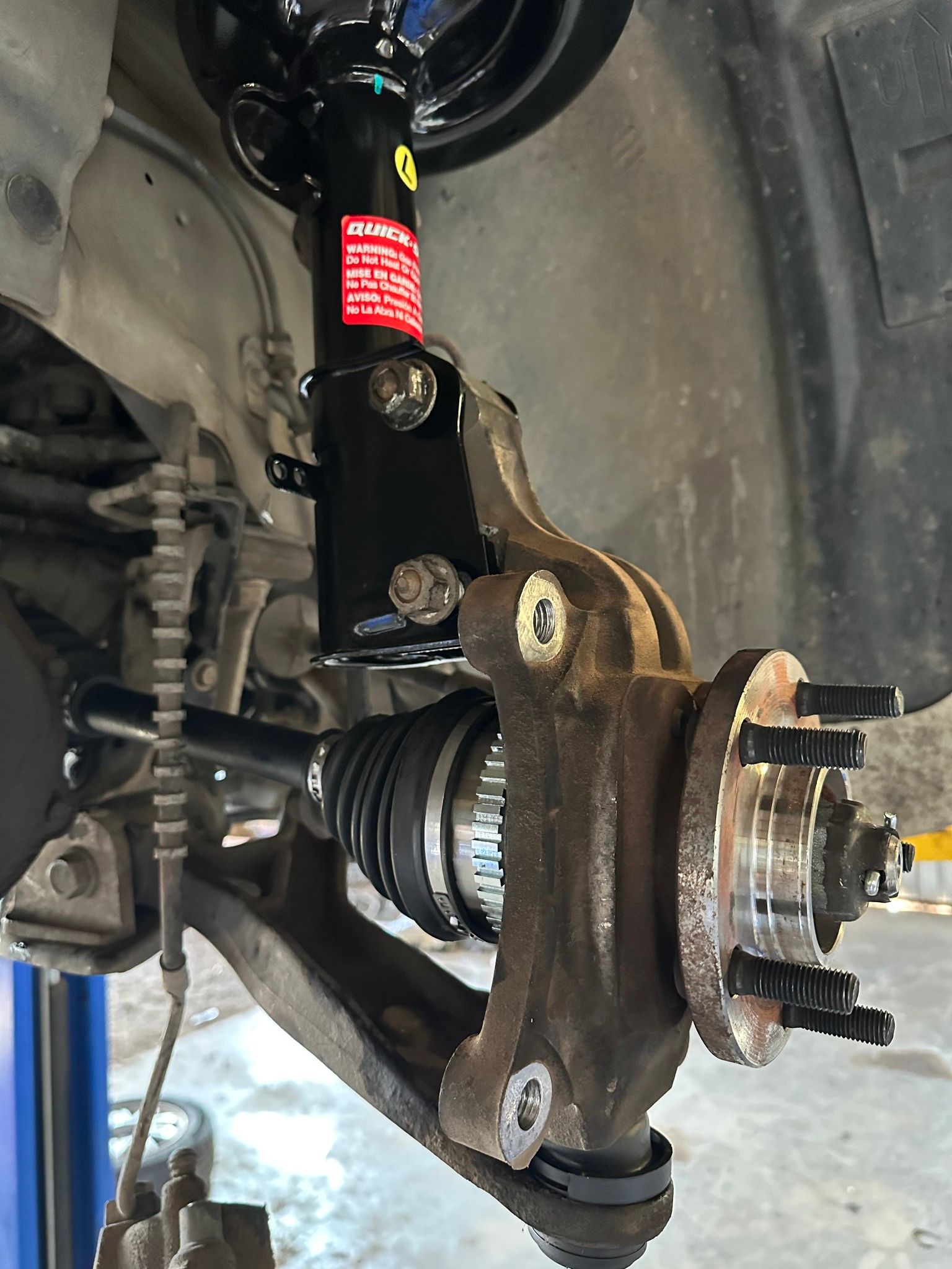 Car wheel hub and suspension assembly with CV axle and brake rotor, viewed from inside the wheel well