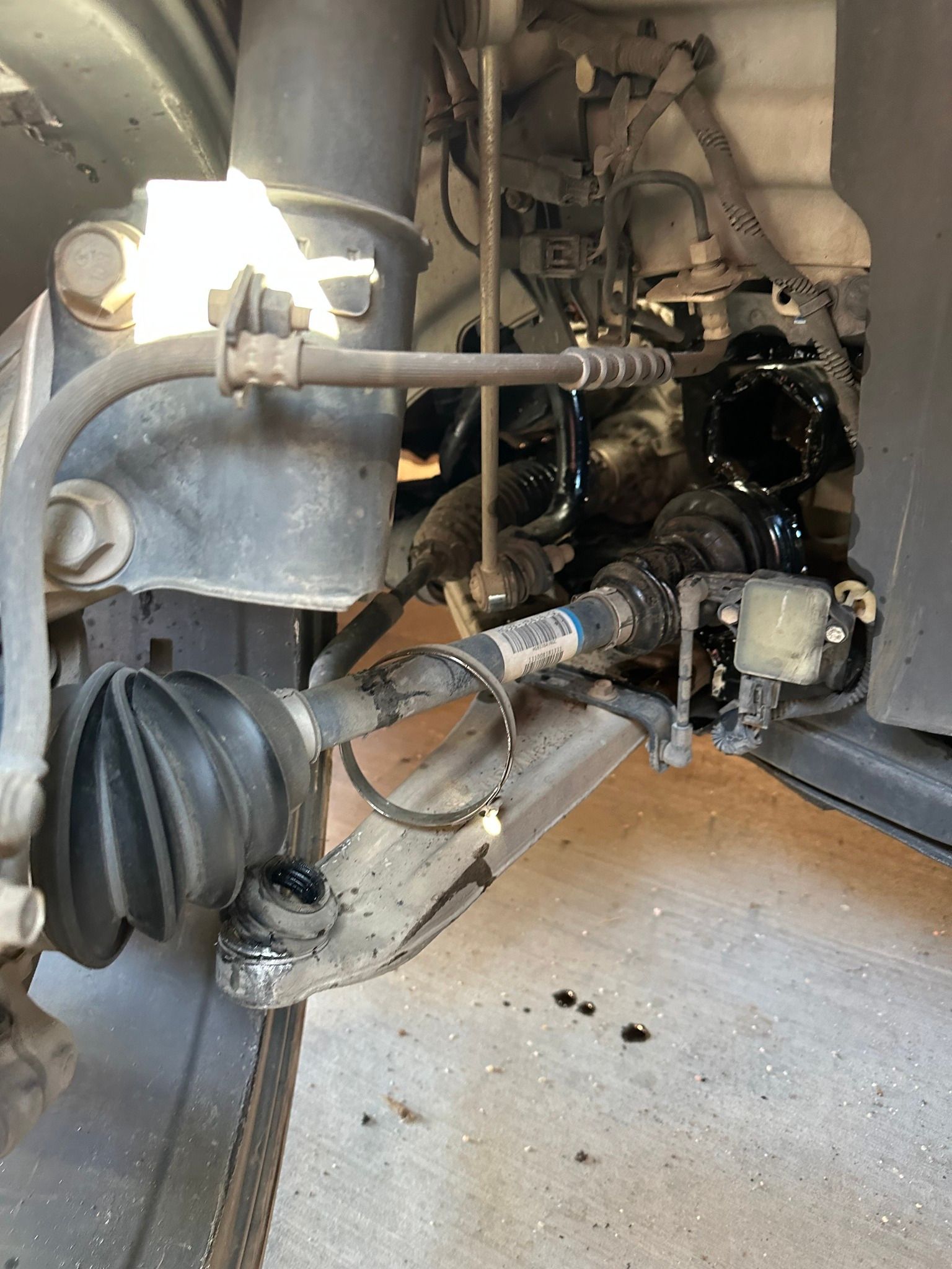 Close-up of a car’s exposed front suspension and axle components in a garage.
