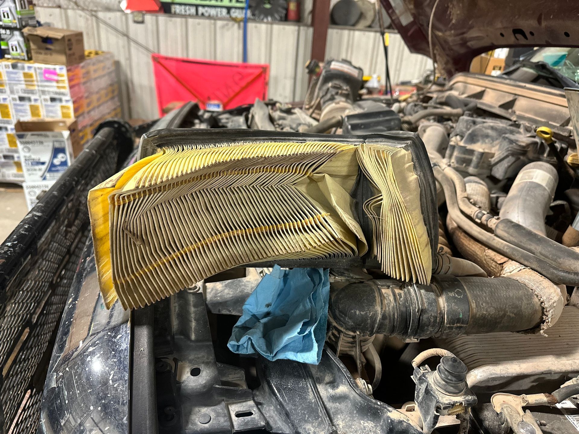 Yellow filter wrapped over engine intake in a cluttered vehicle engine bay.