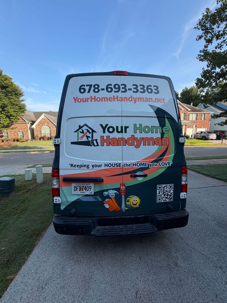 Handyman service van parked on a residential street, with large red and black business signage on the back.