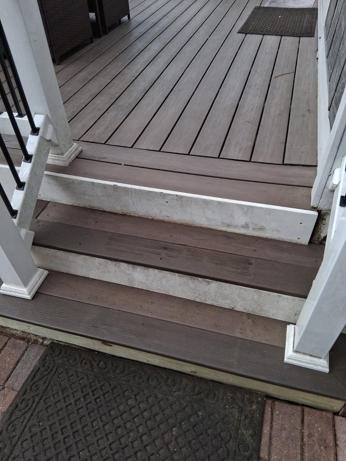 Front porch steps with white railings and brown wooden decking, viewed from ground level.