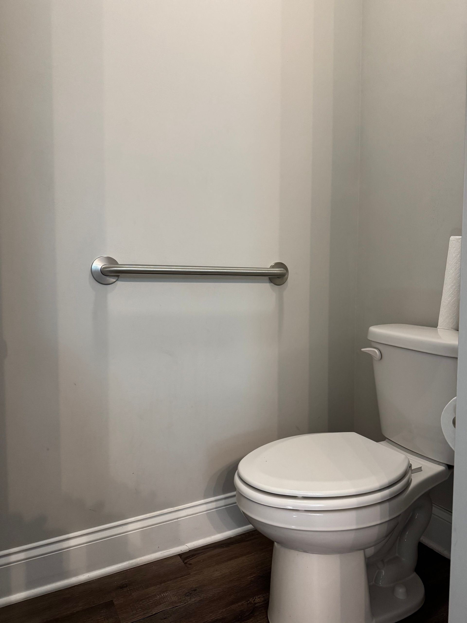 Bathroom toilet with chrome grab bar on the wall nearby