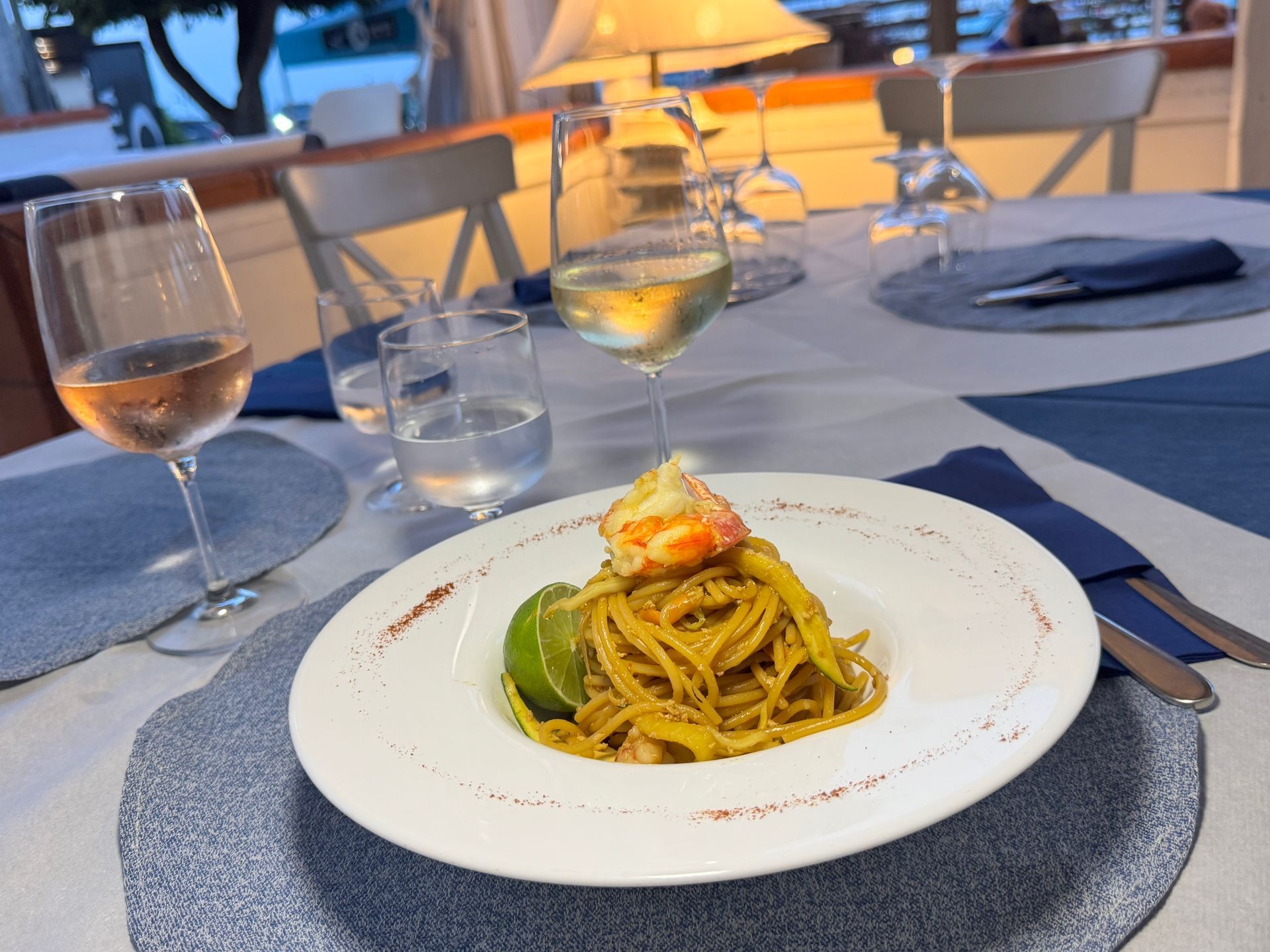 Elegante tavolo da pranzo con pasta e cocktail al tramonto in riva al mare