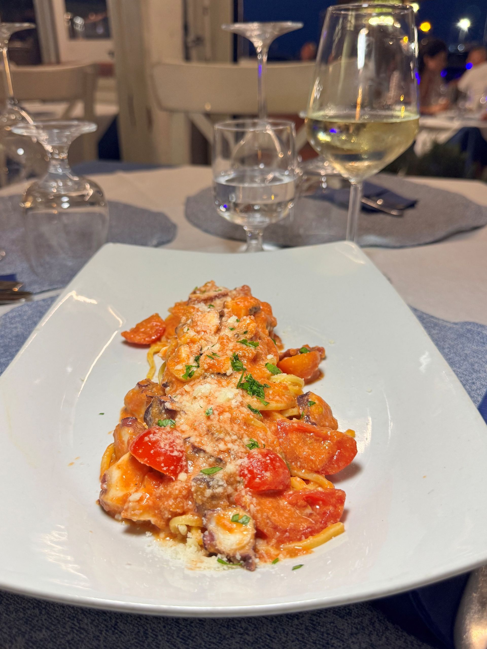 Pasta al sugo di pomodoro ed erbe aromatiche servita su una tovaglia bianca a un tavolo da pranzo elegante.