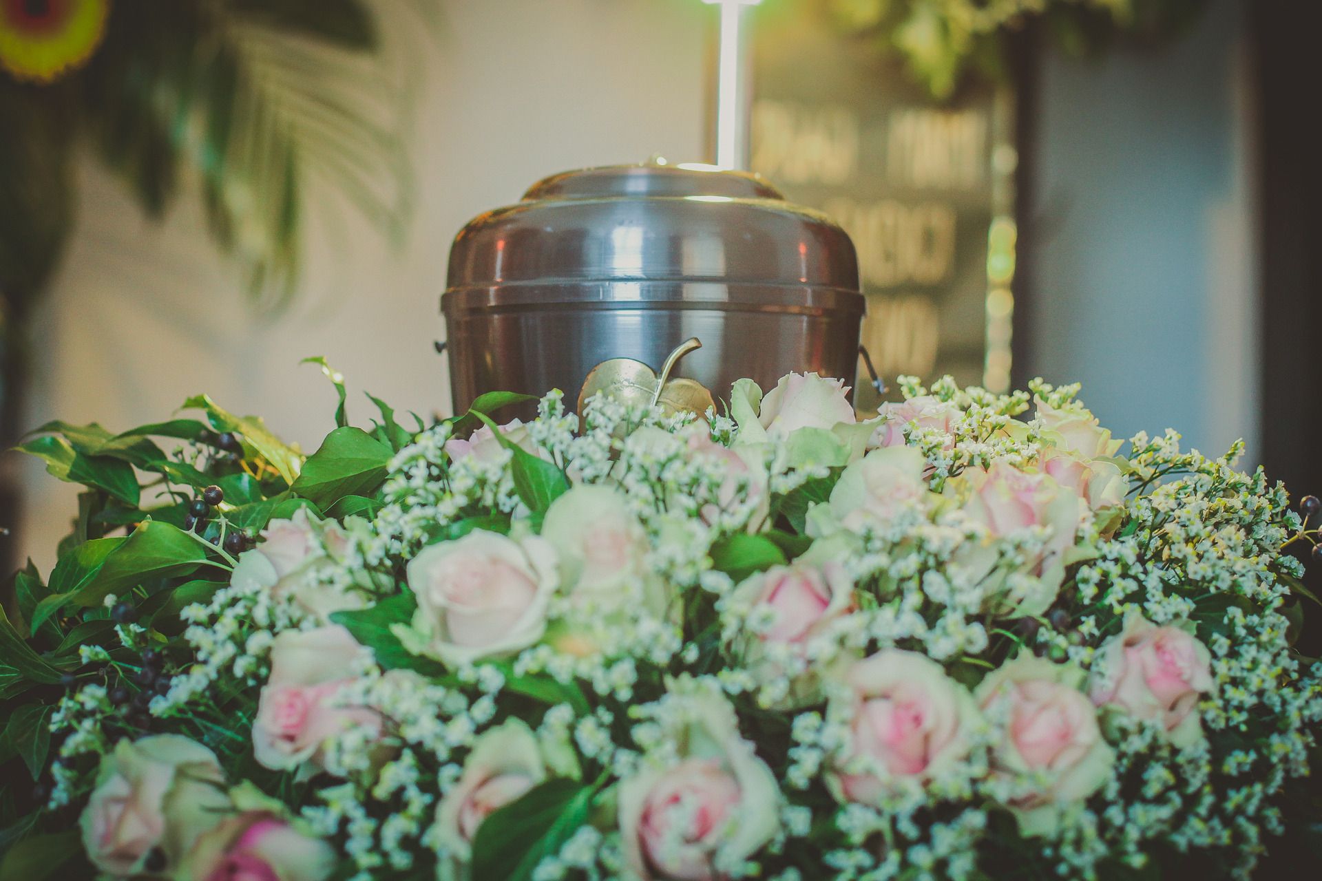 A metal urn surrounded by pink roses and baby 's breath.