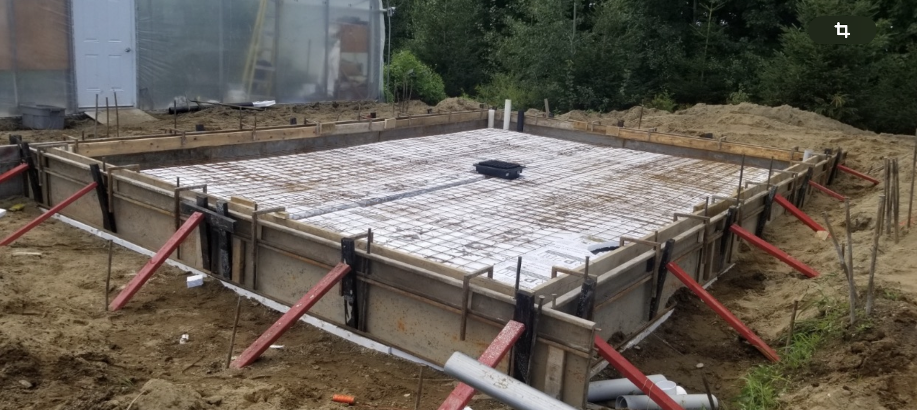 Une base en béton pour une maison est en train d'être construite dans la terre.