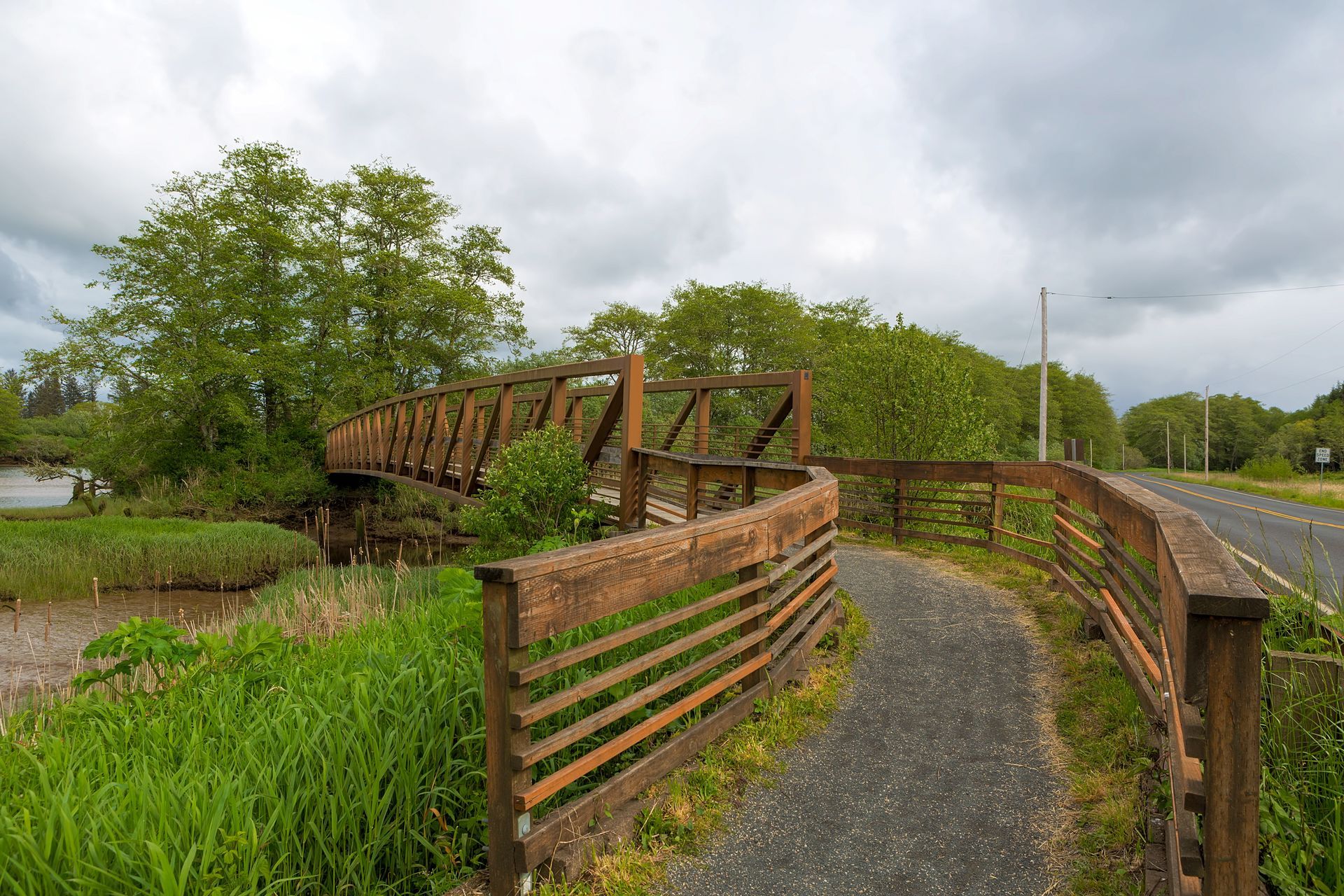 A wooden bridge over a river with a path leading to it.