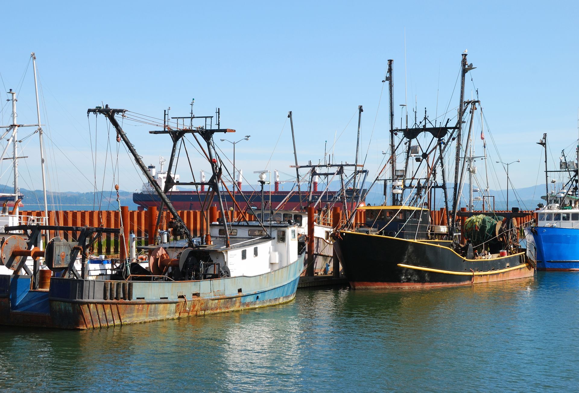 Several boats are docked in a harbor on a sunny day