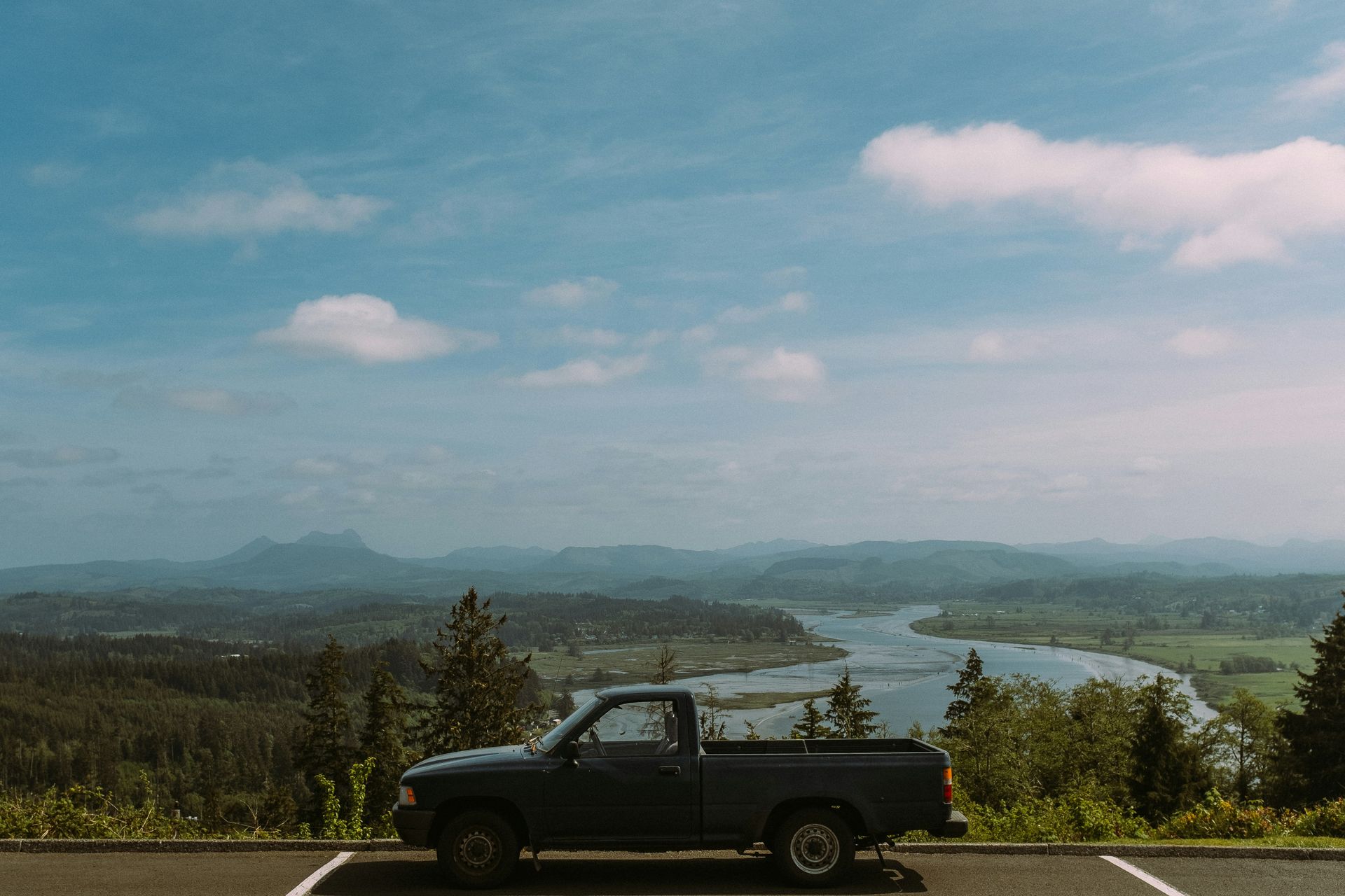 A pickup truck is parked on the side of the road overlooking a river.