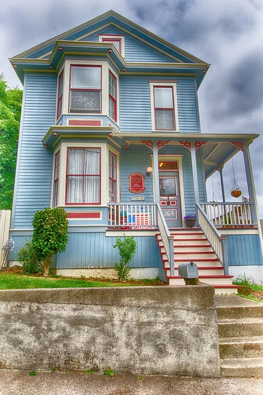 A blue house with a red and white porch and stairs