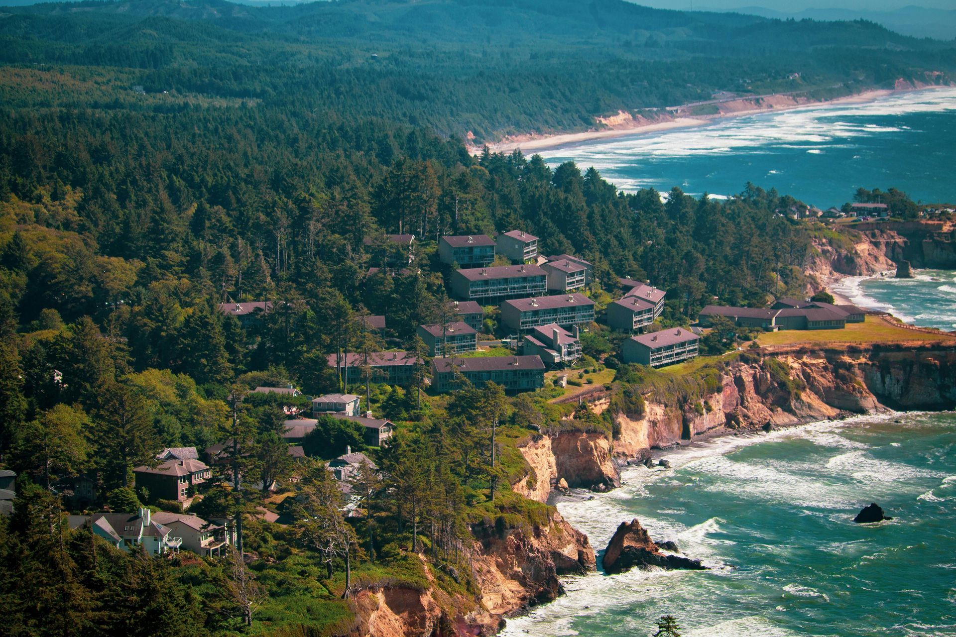 An aerial view of a small town on a cliff overlooking the ocean.