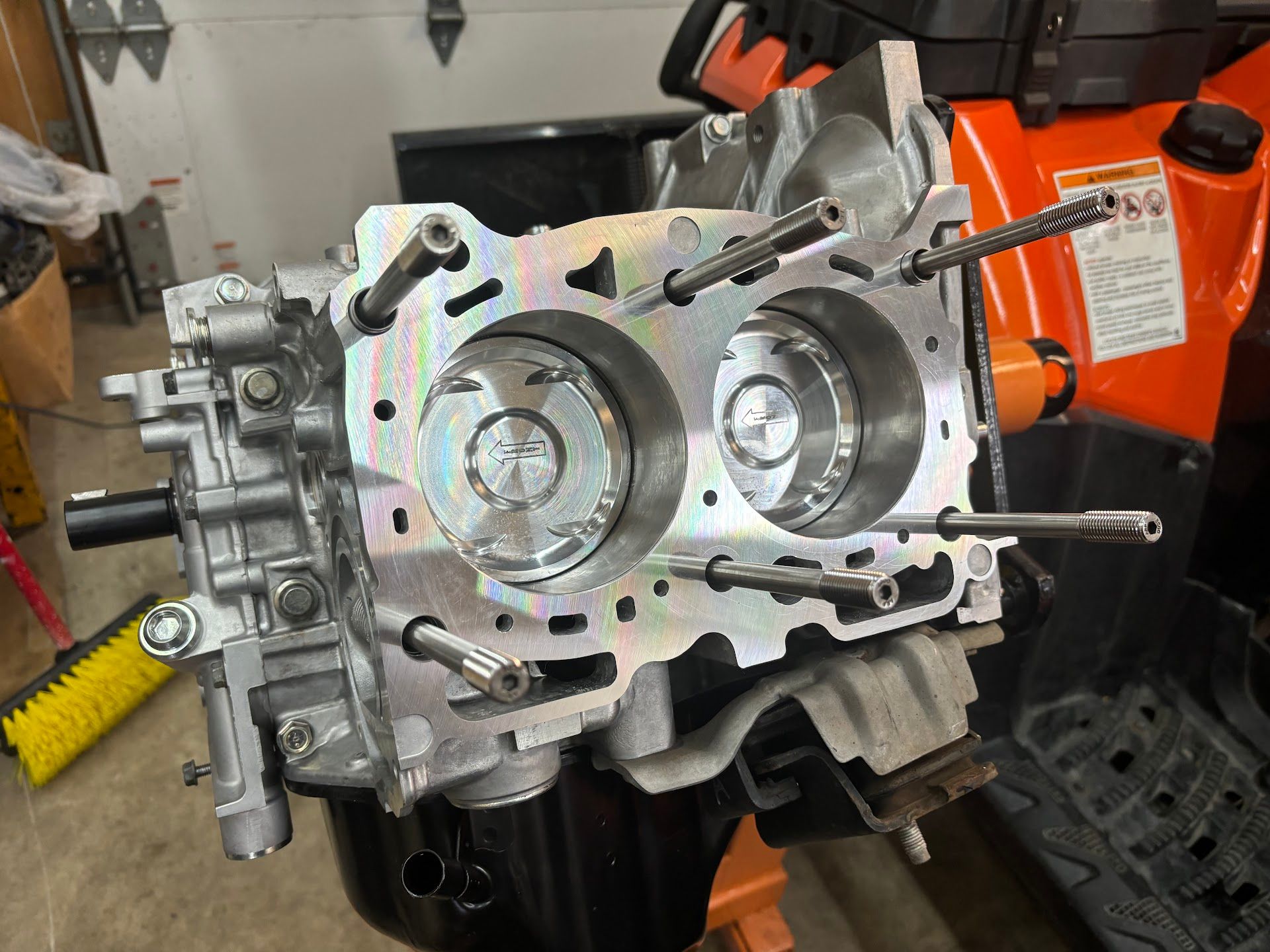 A clean, disassembled engine block with two visible pistons, sitting on a stand in a garage. | Teter Automotive