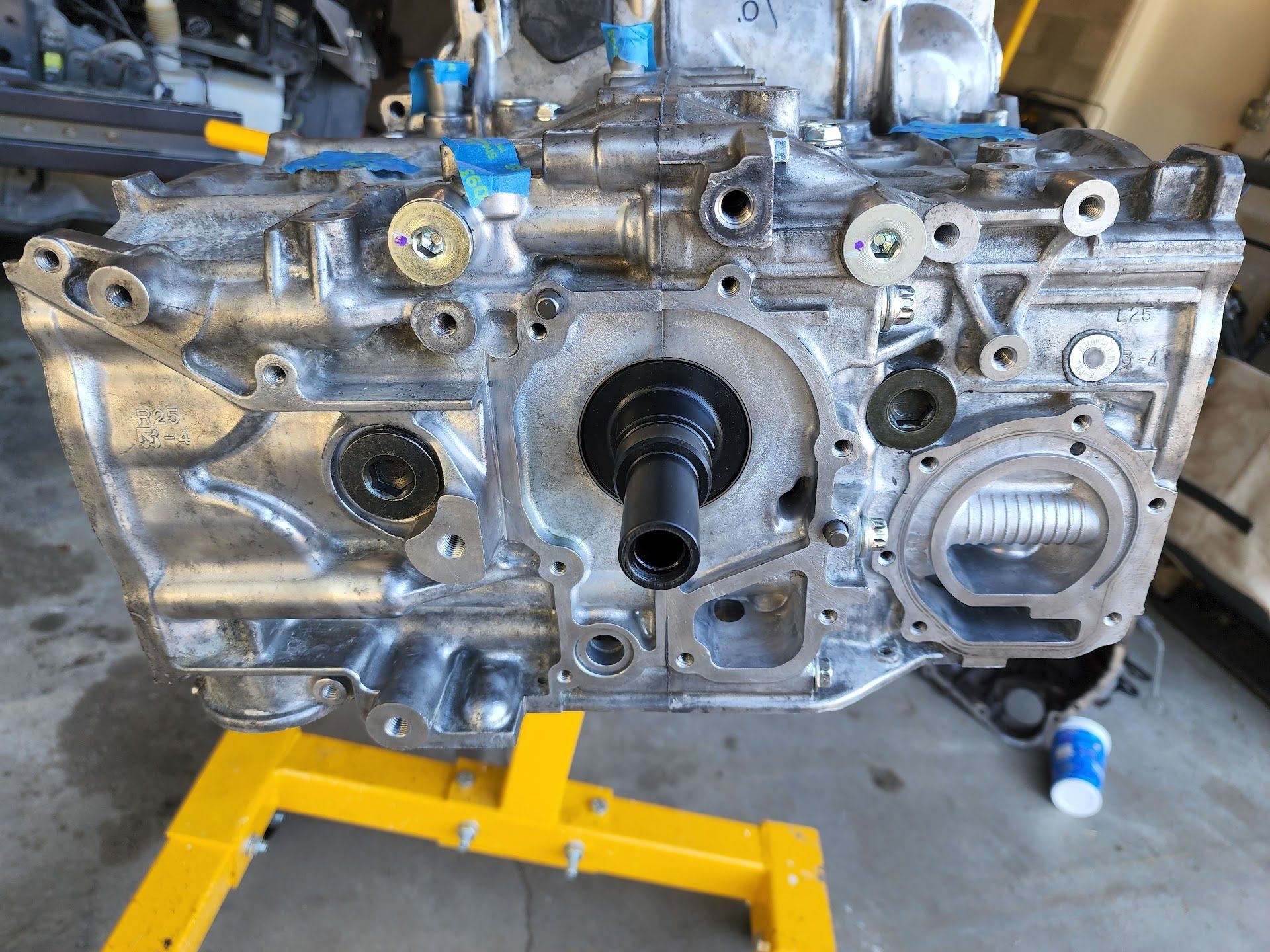 A disassembled aluminum car engine block mounted on a yellow stand in a garage setting. | Teter Automotive