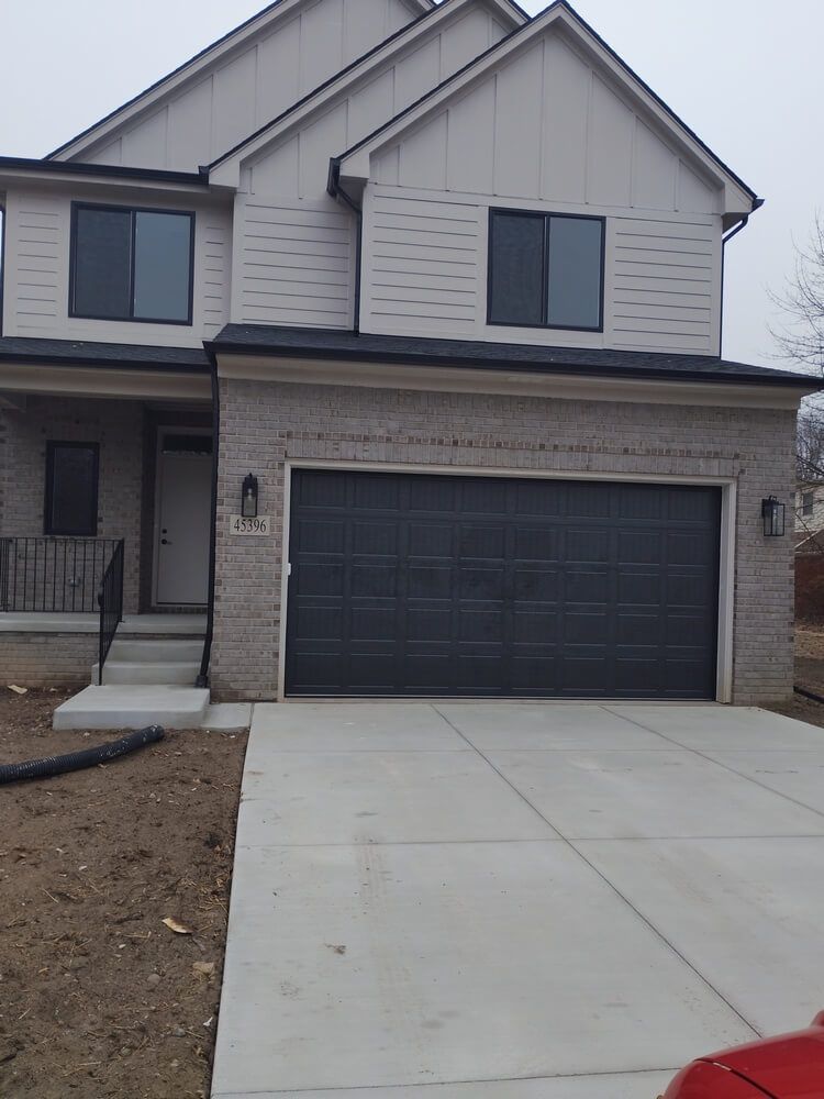 Suburban two-story house with a black garage door and concrete driveway