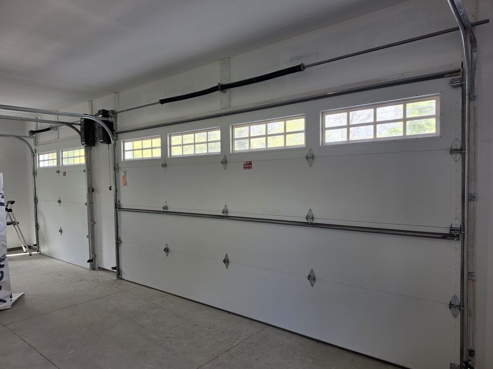 White sectional garage door with windows in a clean, empty garage interior