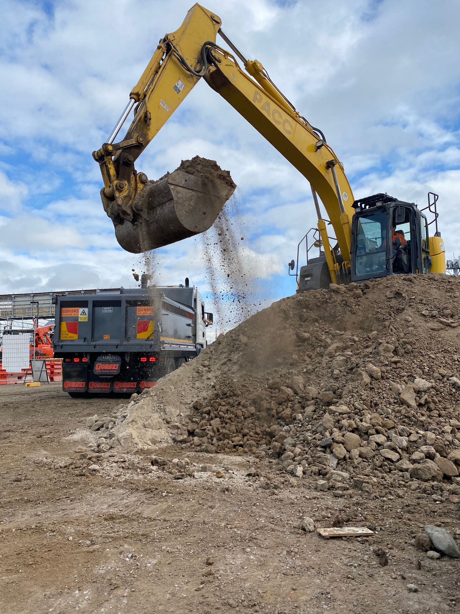 A yellow excavator is loading dirt into a dump truck.
