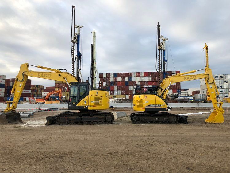 Two yellow excavators are parked next to each other in a dirt field.