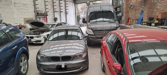 Varios coches aparcados se agolpaban en una calle estrecha, entre ellos un sedán gris