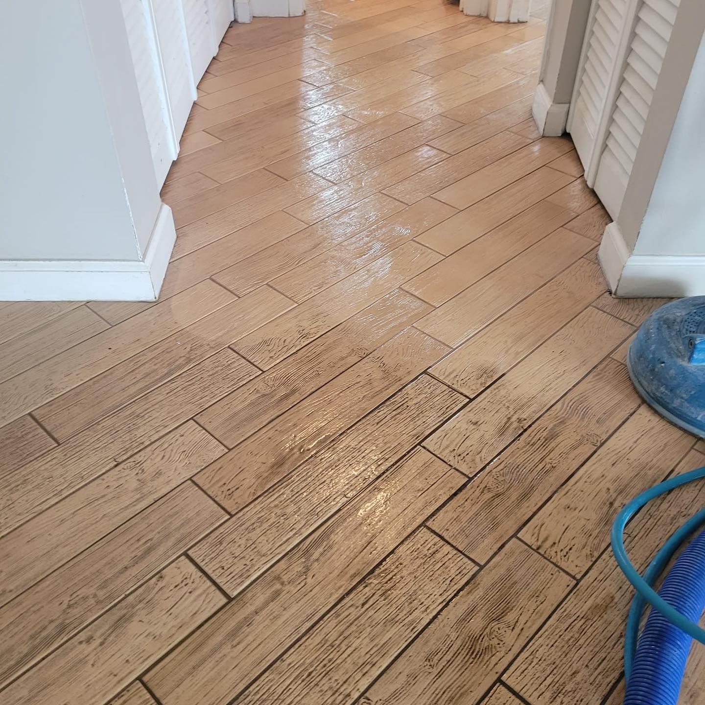 A hallway with a wooden floor and a vacuum cleaner.