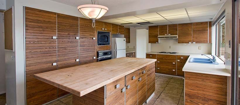 Kitchen with wood cabinetry, island, and tile flooring. A light fixture hangs from the ceiling.
