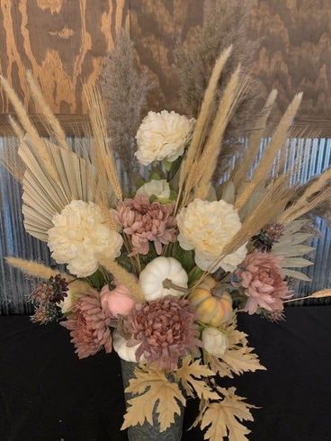 A vase filled with flowers and pumpkins is sitting on a table.
