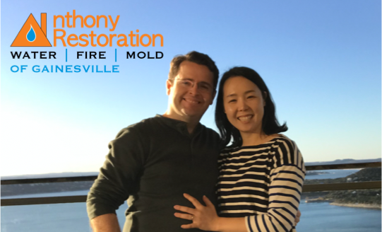 A man and woman are posing for a picture with anthony restoration in the background