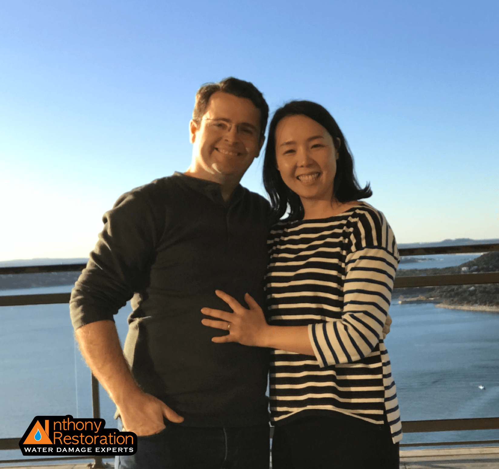 A man and a woman are posing for a picture with an anthony restoration logo in the corner