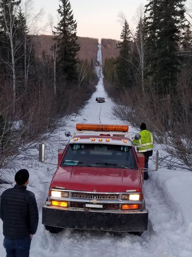 A red chevrolet truck is driving down a snowy road