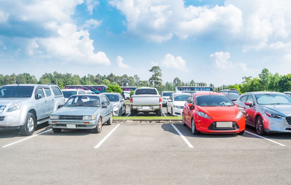 A row of cars are parked in a parking lot.