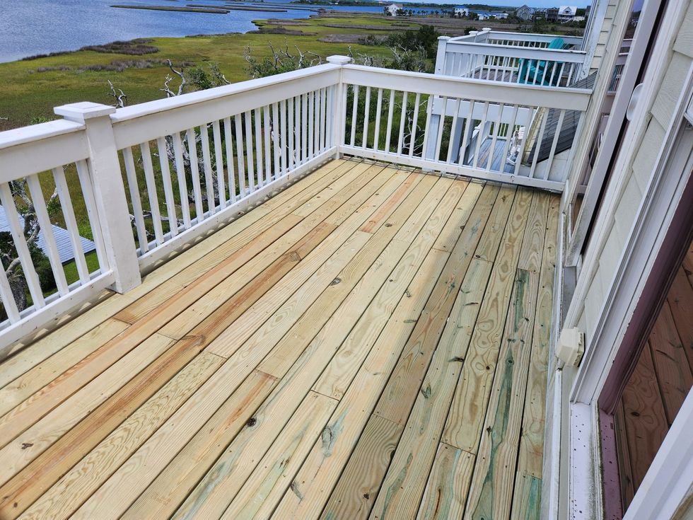 Wooden deck with white railing overlooking a coastal marsh and water view