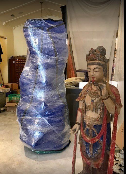 A statue  standing next to a large blue bag.