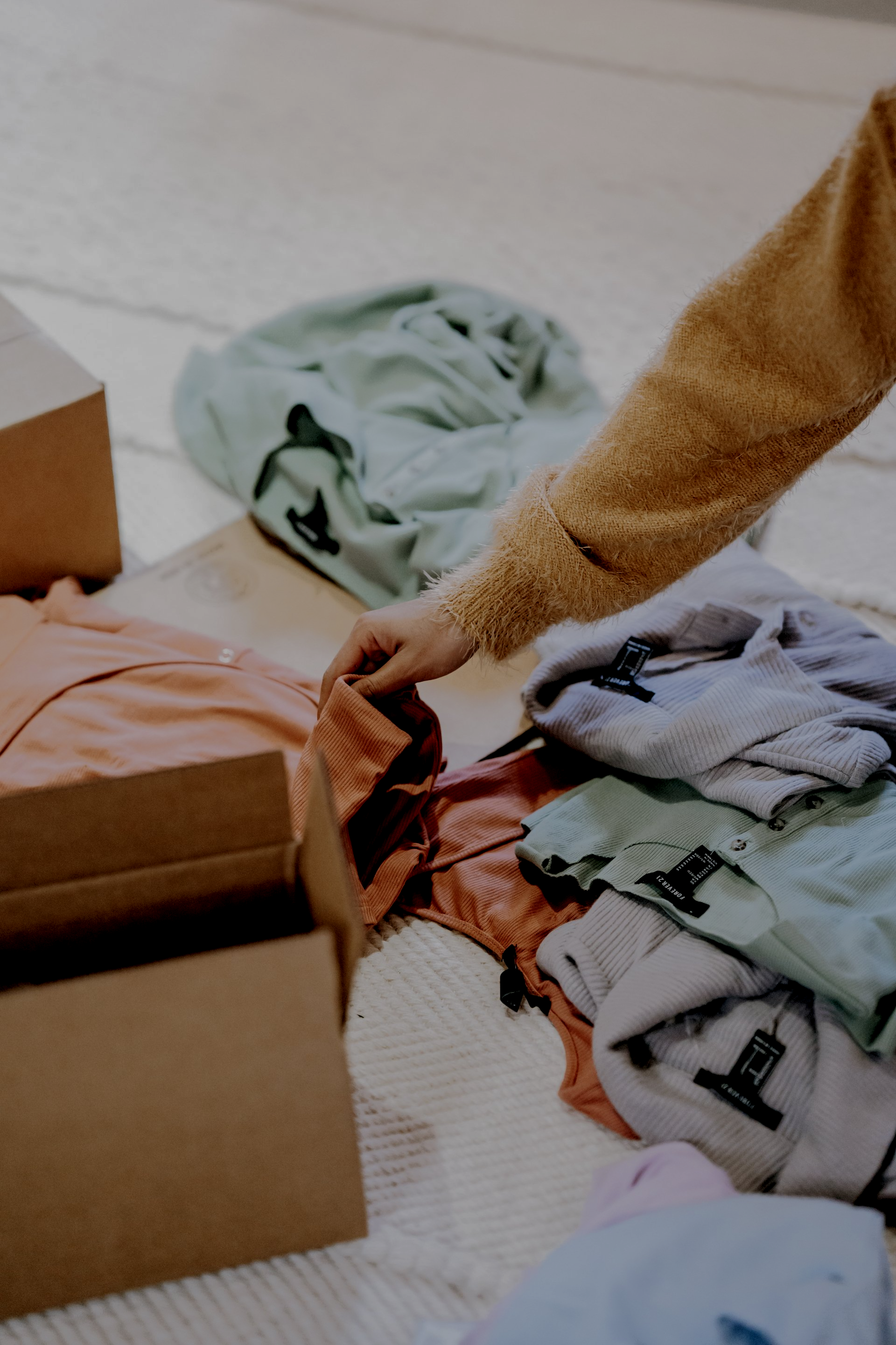 A person is putting clothes in a cardboard box.