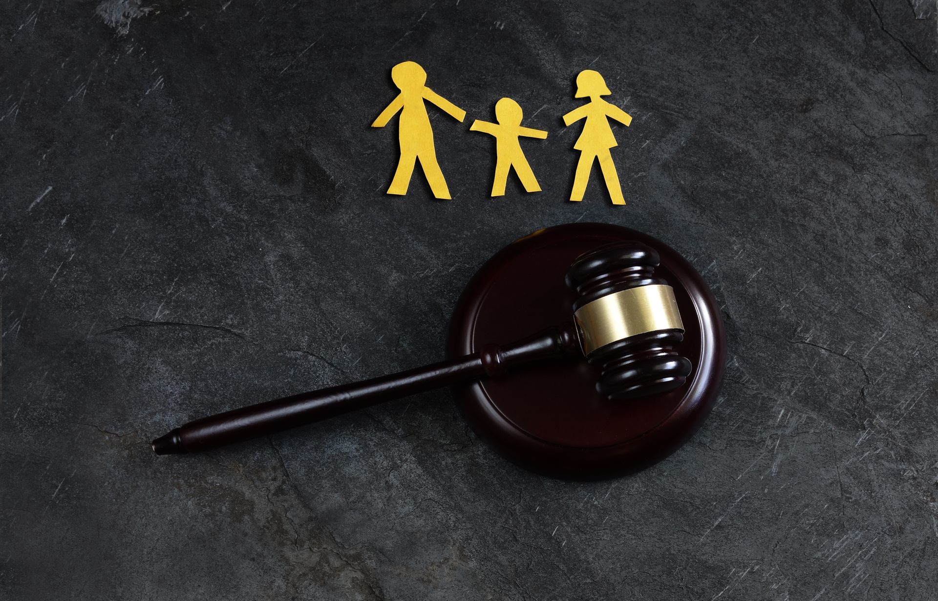 A wooden judge 's gavel is sitting on a table next to a group of paper people.