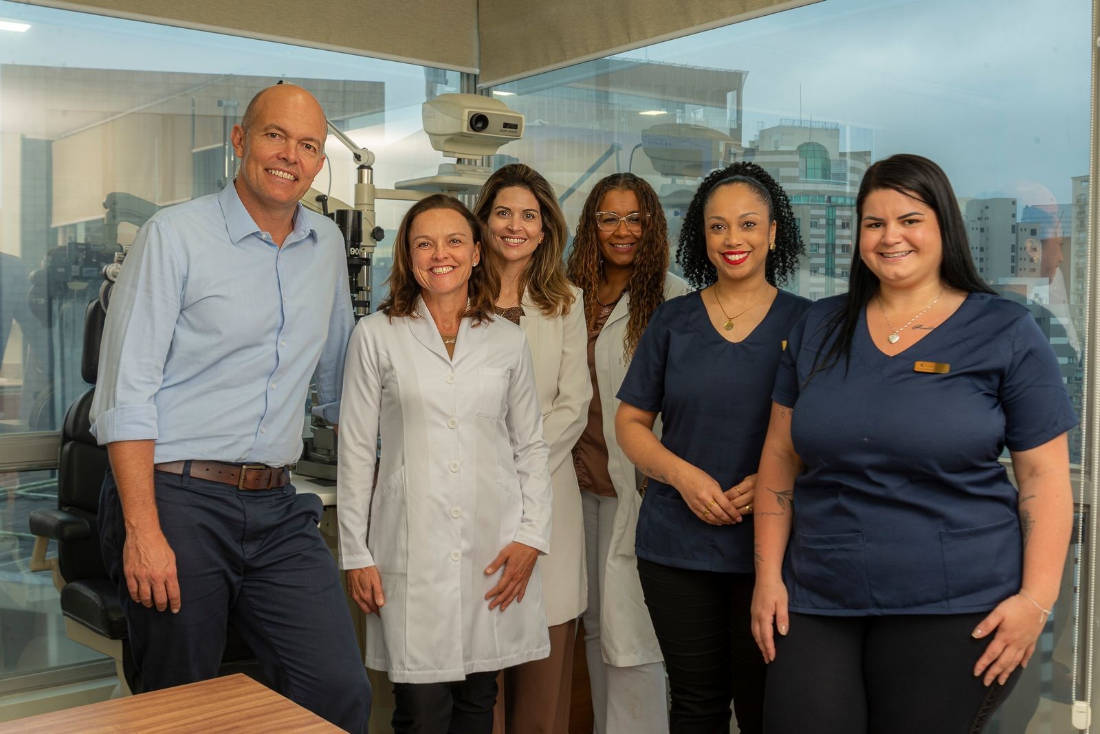 Grupo de profissionais médicos, em ambiente clínico, sorrindo.