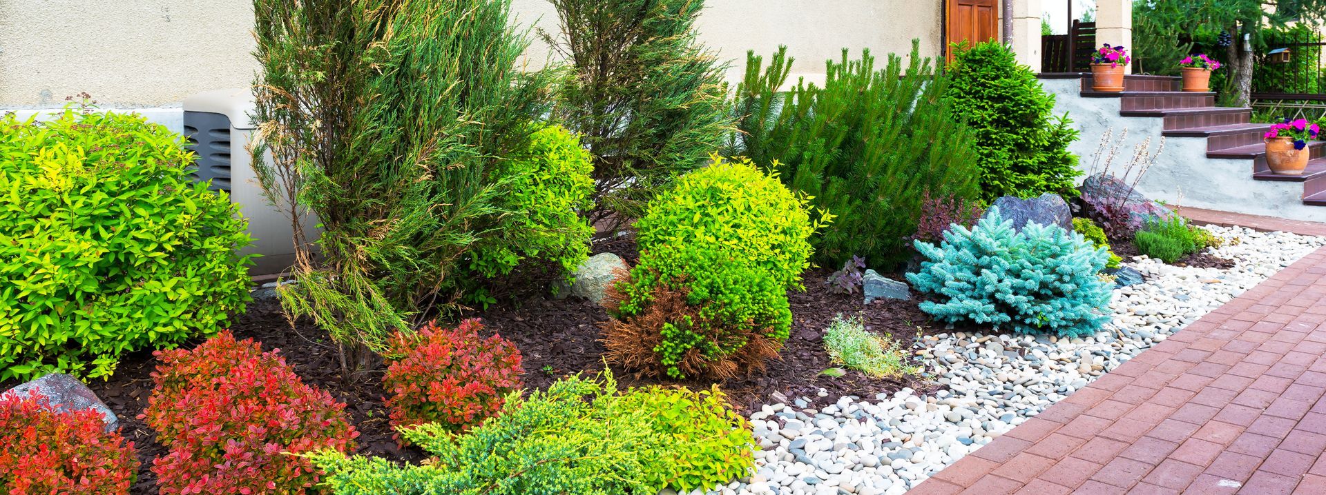 A vibrant landscaped garden with various colorful shrubs and a brick pathway.