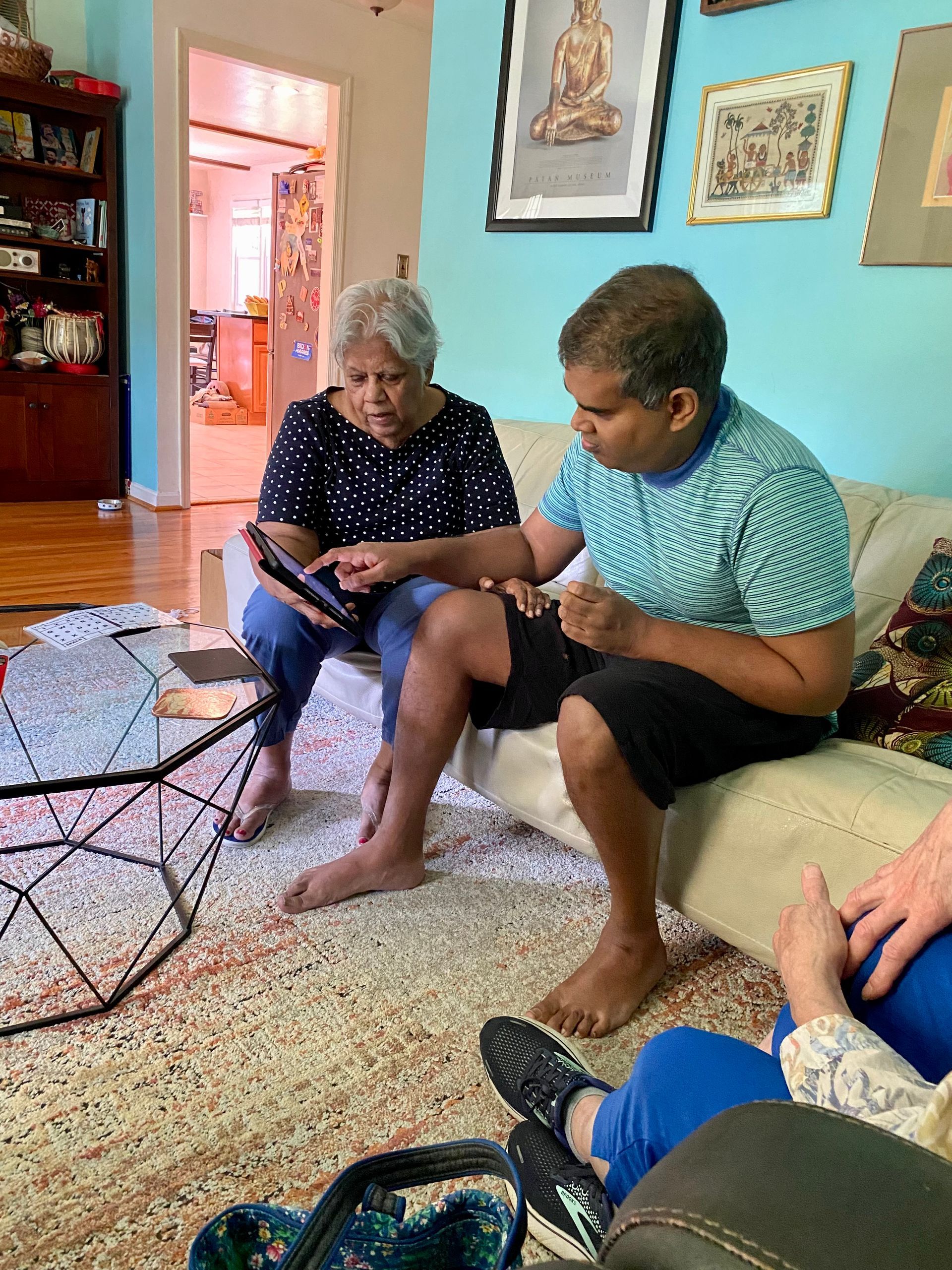 Two people looking at a tablet on a couch in a living room; one is holding it.