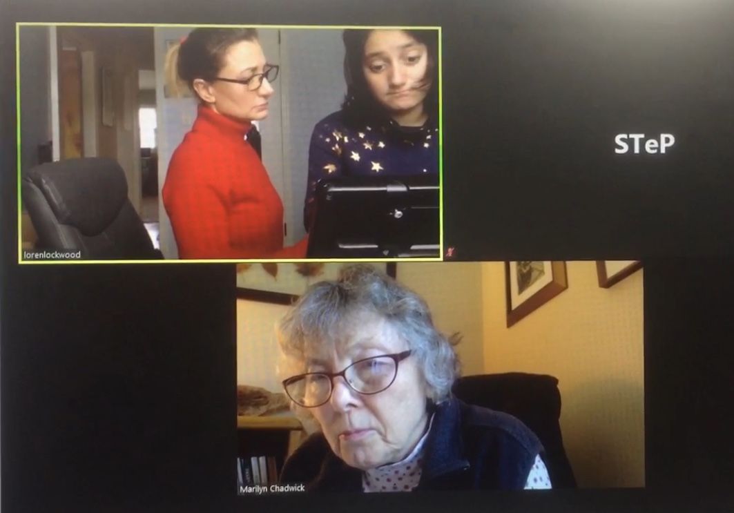 Zoom meeting: Three women; two stand near a screen; one elderly woman at the bottom.