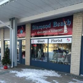 Storefront for Diamond Beach Jewellery & Flowers, with Gimli Florist sign under a covered walkway.