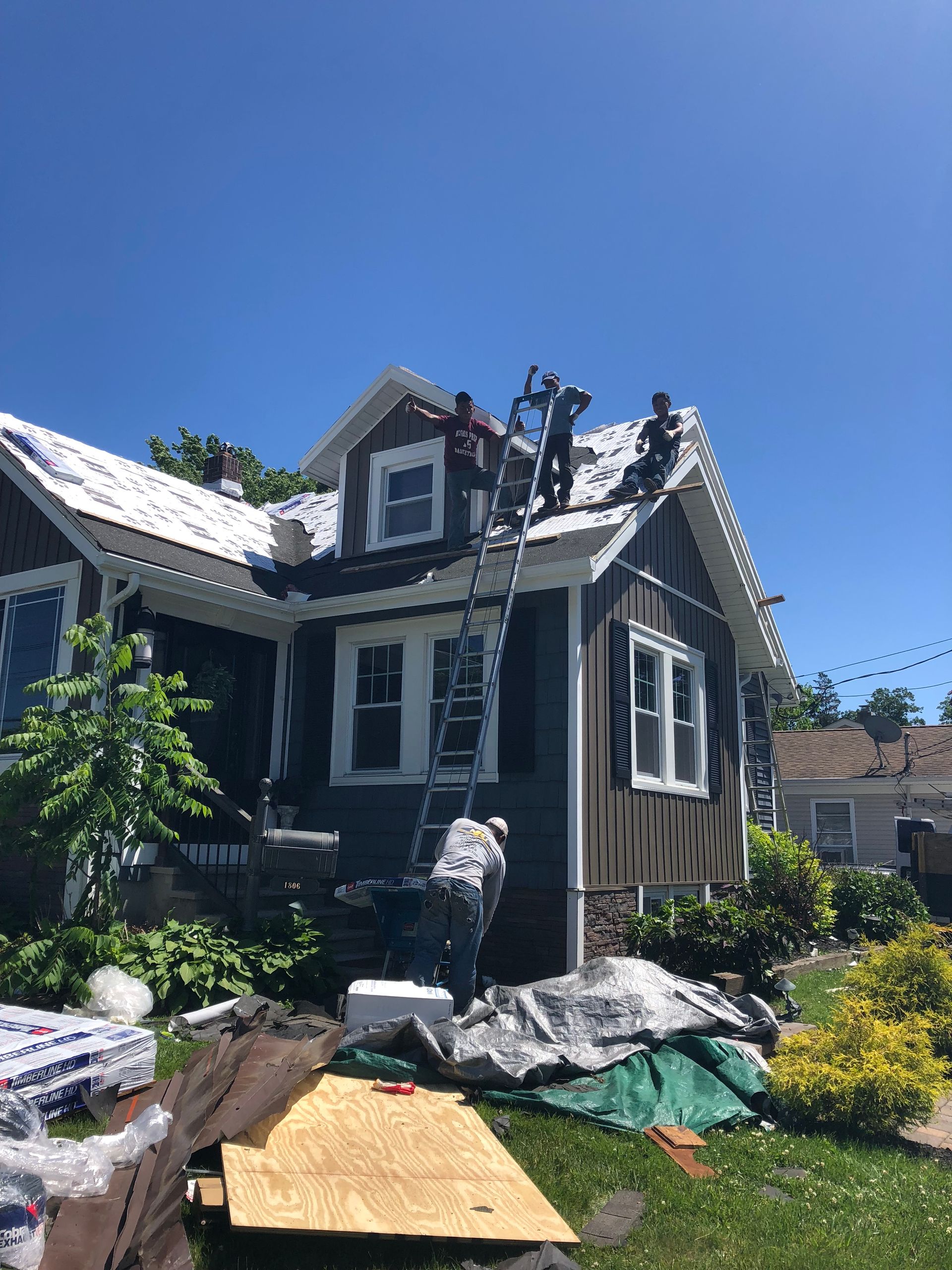 Damaged house with roof repair work, debris, and scaffolding under a clear blue sky